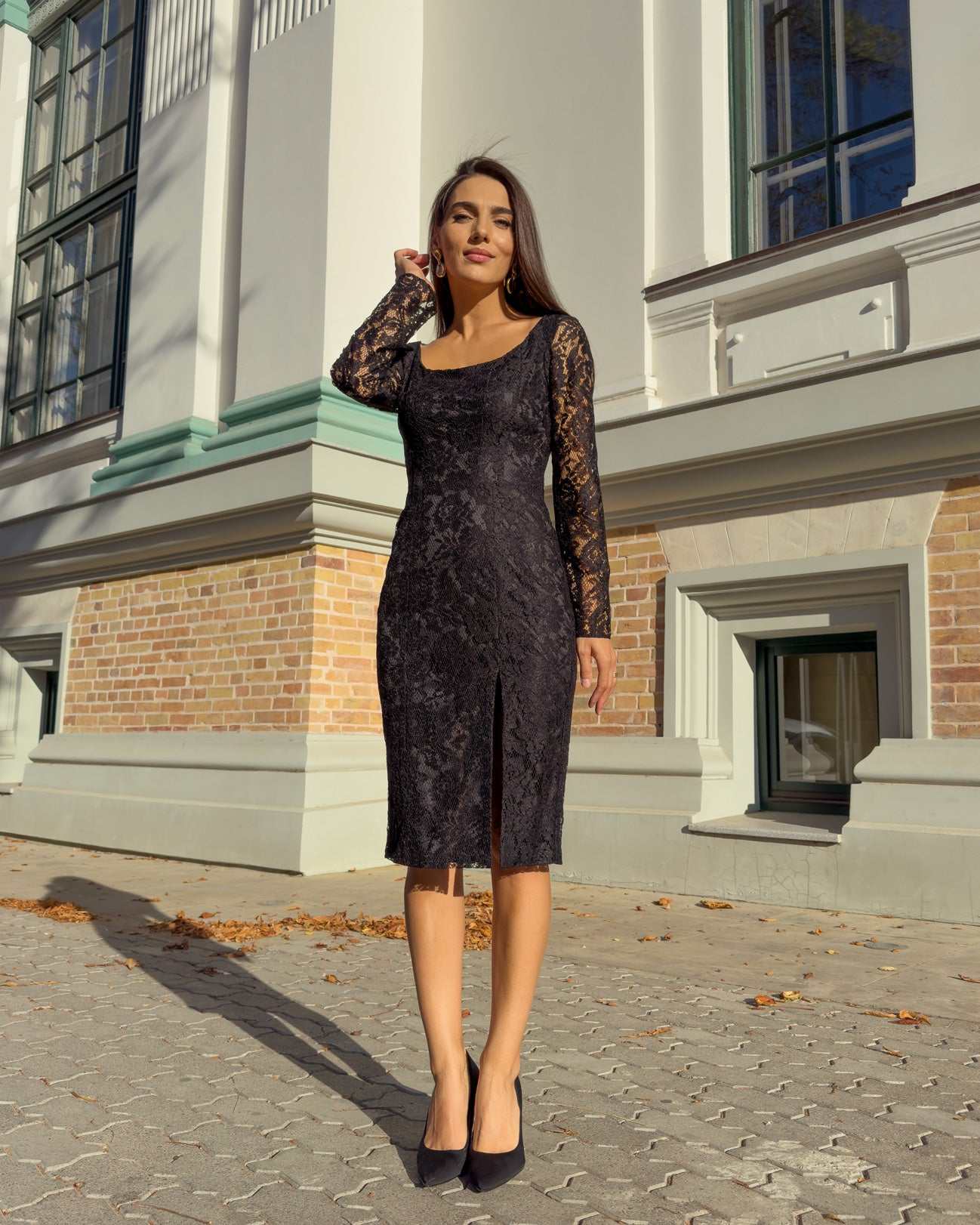 Rochie neagra din dantelă cu mâneci lungi și decolteu mic, ajustată pe corp.