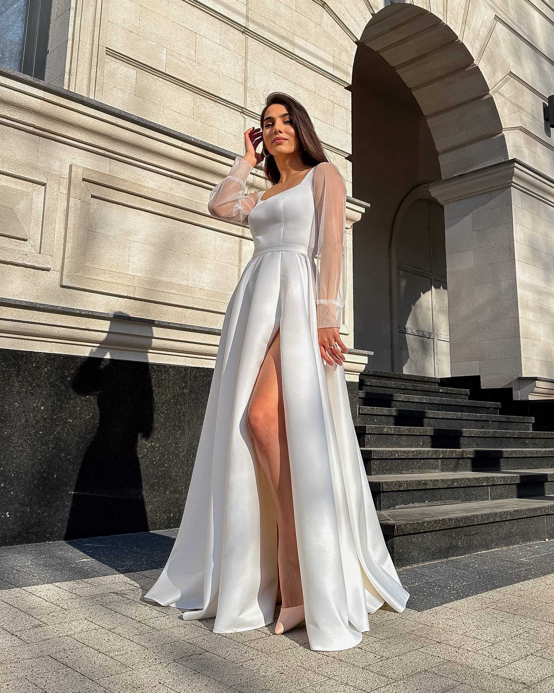 Rochie de mireasa albă lungă din satin regal cu șliț și mâneci transparente din tull.