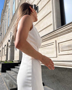 Rochie cocktail albă elegantă fără mâneci, croială ajustată, slit pe piciorul stâng.