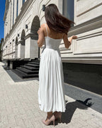 Rochie alba elegantă cu bretele și slit, accesorizată cu centură, vedere din spate.