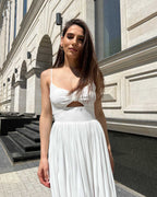 Rochie alba elegantă midi cu bretele și slit, accesorizată cu centură.