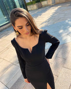 Rochie eleganta cocktail cu slit pe piciorul stâng și mâneci lungi, purtată de un model.